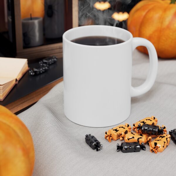 A mug surrounded by pumpkins and candies on a table.