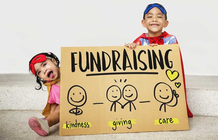 Two children smiling and holding a fundraising sign.