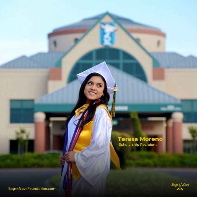 Teresa in a graduation gown smiling in front of children’s hospital.