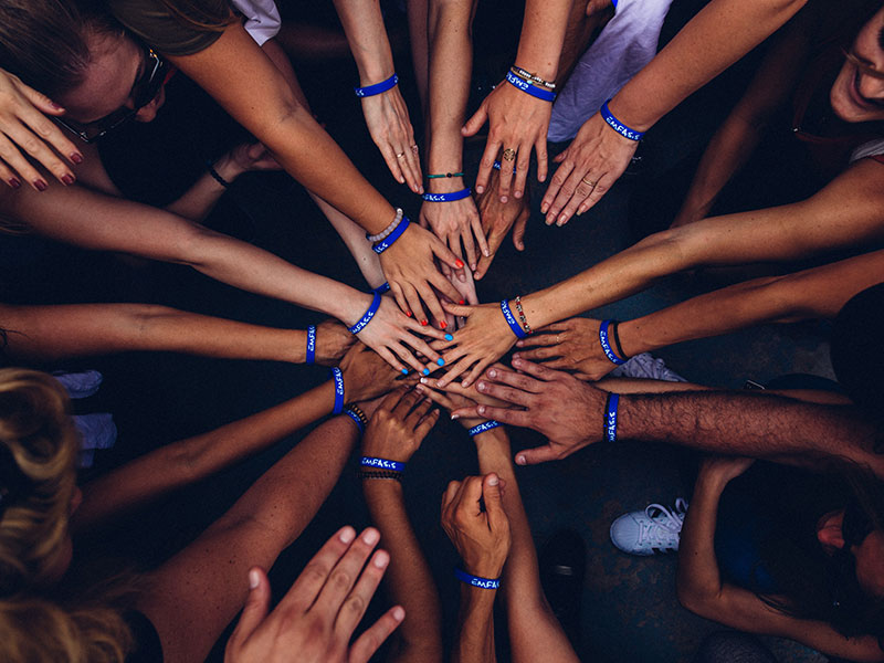 Group of people joining hands in a huddle.